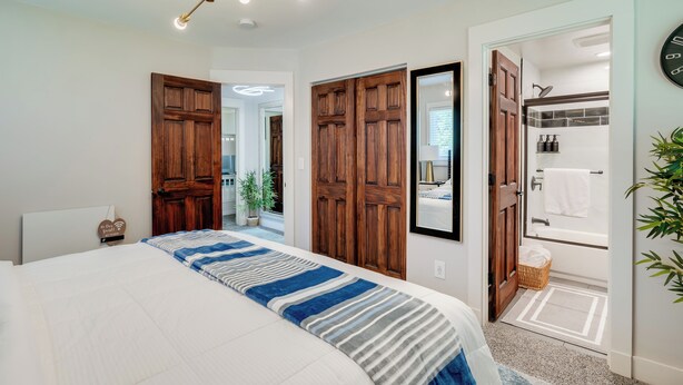 Une chambre avec un grand lit, une armoire en bois et une salle de bain équipée d’une baignoire et d’une douche.
