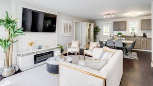 Un salon moderne avec une cheminée, un coin repas et une cuisine.