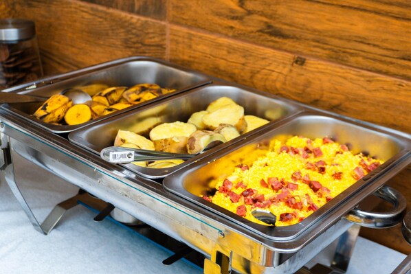 Un buffet proposant divers plats, notamment des pommes de terre, un gratin au jambon et un plat à base de sauce jaune.