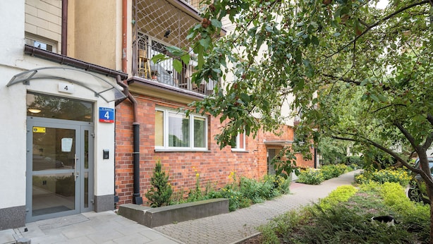 Un bâtiment à la façade en briques, doté d’une entrée en verre et d’un petit jardin agrémenté d’un sentier.