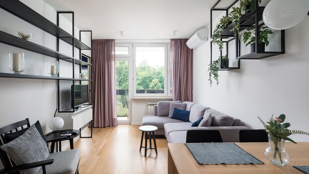 Een moderne woonkamer met een bank, een eettafel en een boekenkast.