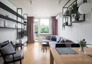 A modern living room with a sofa, a dining table, and a bookshelf. - Elektrownia Powiśle Stylish Apartment (Warszawa)
