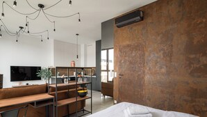 A modern hotel room with a large bed, a desk, a sofa, and a TV.