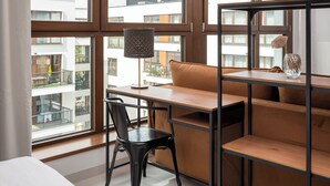 A modern room with a desk, chair, and a large window offering a view of the cityscape.