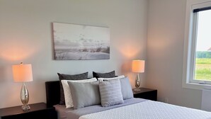 Um quarto com uma cama, duas mesas de cabeceira, um ventilador de teto, uma janela e um quadro na parede.