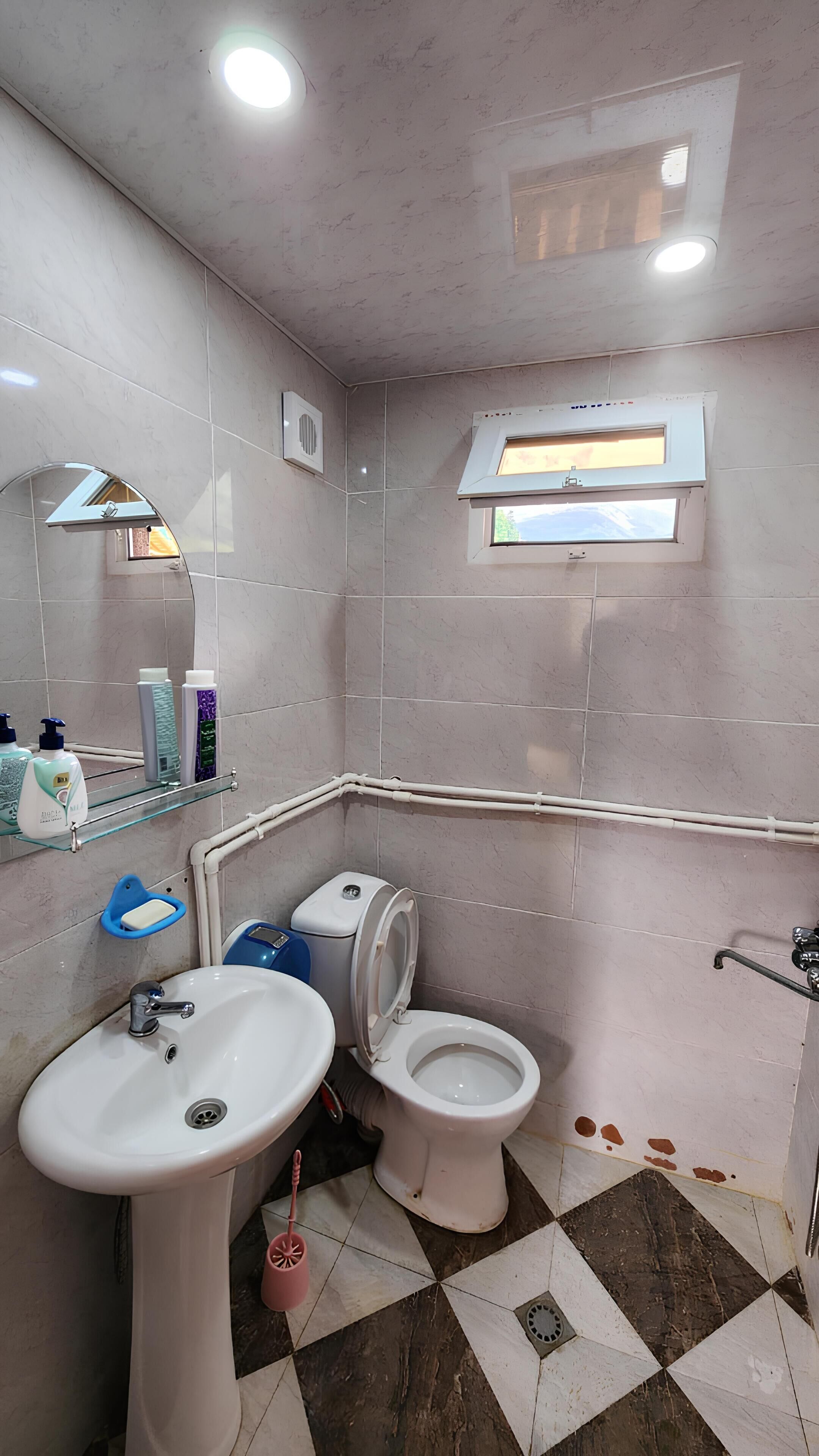 A bathroom with a sink, toilet, and a window.