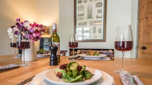 A dining table with a plate of salad, two wine glasses, a bottle of wine, and a pepper grinder. - Olive Cottage, Wickham Market (Wickham Market)