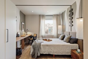 Enjoy a restful stay in this stylish bedroom with a made bed, desk, and city view.