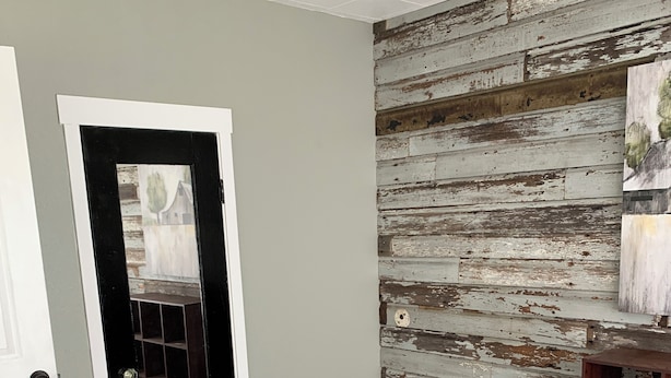 Una habitación con pared de madera, una puerta y piso de madera.