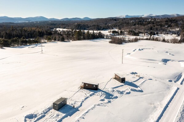 A snow-covered landscape with two cabins and a clear view of distant mountains. - Scenic Tiny Home, Five Minutes to Stowe Main St! (Morristown)