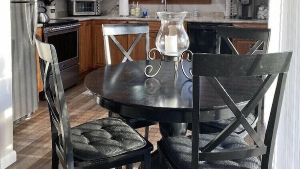 Una cucina con mobili in legno, un frigorifero in acciaio inossidabile, un forno a microonde e un tavolo da pranzo con quattro sedie.