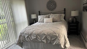 Una camera da letto con un letto grande, due comodini, una decorazione a parete e una finestra con tende.