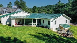 A two-story house with a green roof, a covered porch, and a small outdoor seating area. - Clean, perfect home a mile from historic Waterbury (Waterbury Village Historic District)