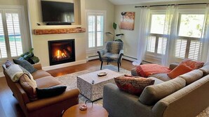 A living room with a fireplace, a television, and a large window with curtains. - Clean, perfect home a mile from historic Waterbury (Waterbury Village Historic District)