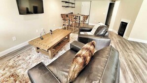 A modern living room with a wooden coffee table, leather sofa, and a TV mounted on the wall. - Clean, perfect home a mile from historic Waterbury (Waterbury Village Historic District)