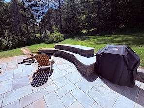An outdoor patio with Adirondack chairs, a stone fire pit, and a Weber grill. - Clean, perfect home a mile from historic Waterbury (Waterbury Village Historic District)