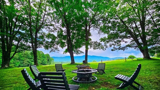A grassy outdoor area with four black lounge chairs and a circular fire pit. - Rustic Farmstay, Bucolic retreat w/Endless Views (Stowe)