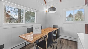 A modern dining area with a wooden table, black chairs, and pendant lighting. - New Stowe remodel, perfect location,many amenities (Stowe)