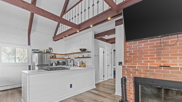 A modern kitchen with white cabinetry, a central island, and a brick fireplace. - New Stowe remodel, perfect location,many amenities (Stowe)