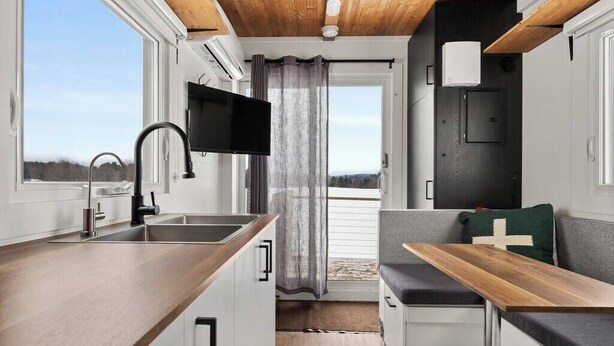 A compact kitchenette with a wooden countertop, a sink, and a flat-screen TV mounted above it.