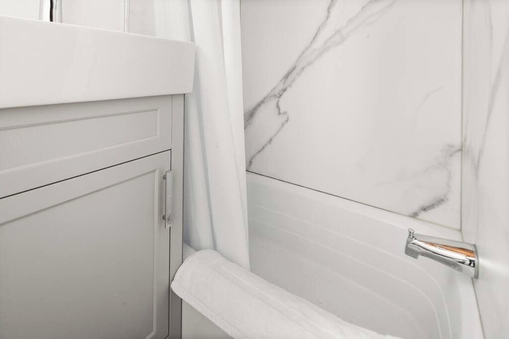 Ein Badezimmer mit weißen Marmorwänden, einer weißen Badewanne und einem weißen Handtuchhalter.