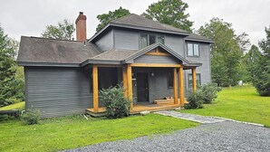 A two-story house with a porch, a chimney, and a well-maintained lawn. - Large house heart of Stowe, amazing river for kids (Stowe)