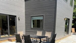 A modern house with a patio area featuring a dining table and chairs. - Large house heart of Stowe, amazing river for kids (Stowe)
