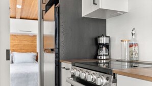 Cocina compacta con estufa, cafetera y una botella de agua.