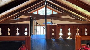 Un dormitorio en el ático con vigas de madera, techo inclinado y vistas al exterior.