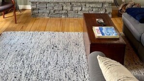 Una sala de estar acogedora con una chimenea de piedra, vigas de madera en el techo y una zona de estar confortable.