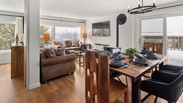 A spacious living room with a wooden dining table set for four, a sofa, and a coffee table. - Stunning views of Stowe, two bedroom, location! (Stowe)
