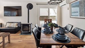 A dining area with a wooden table set for four, black chairs, and a fireplace. - Stunning views of Stowe, two bedroom, location! (Stowe)