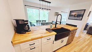 A modern kitchen with a wooden countertop, white cabinets, a built-in sink, and a coffee maker. - Cute two bedroom condo close to Stowe Mountain (Stowe)