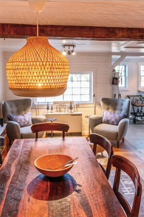 Un coin repas avec une table en bois, des chaises et un luminaire suspendu.