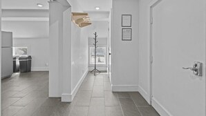 A modern hallway with a tiled floor, white walls, and a door on the right.