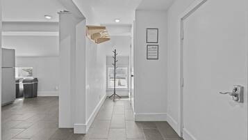 A modern hallway with a tiled floor, white walls, and a door on the right.