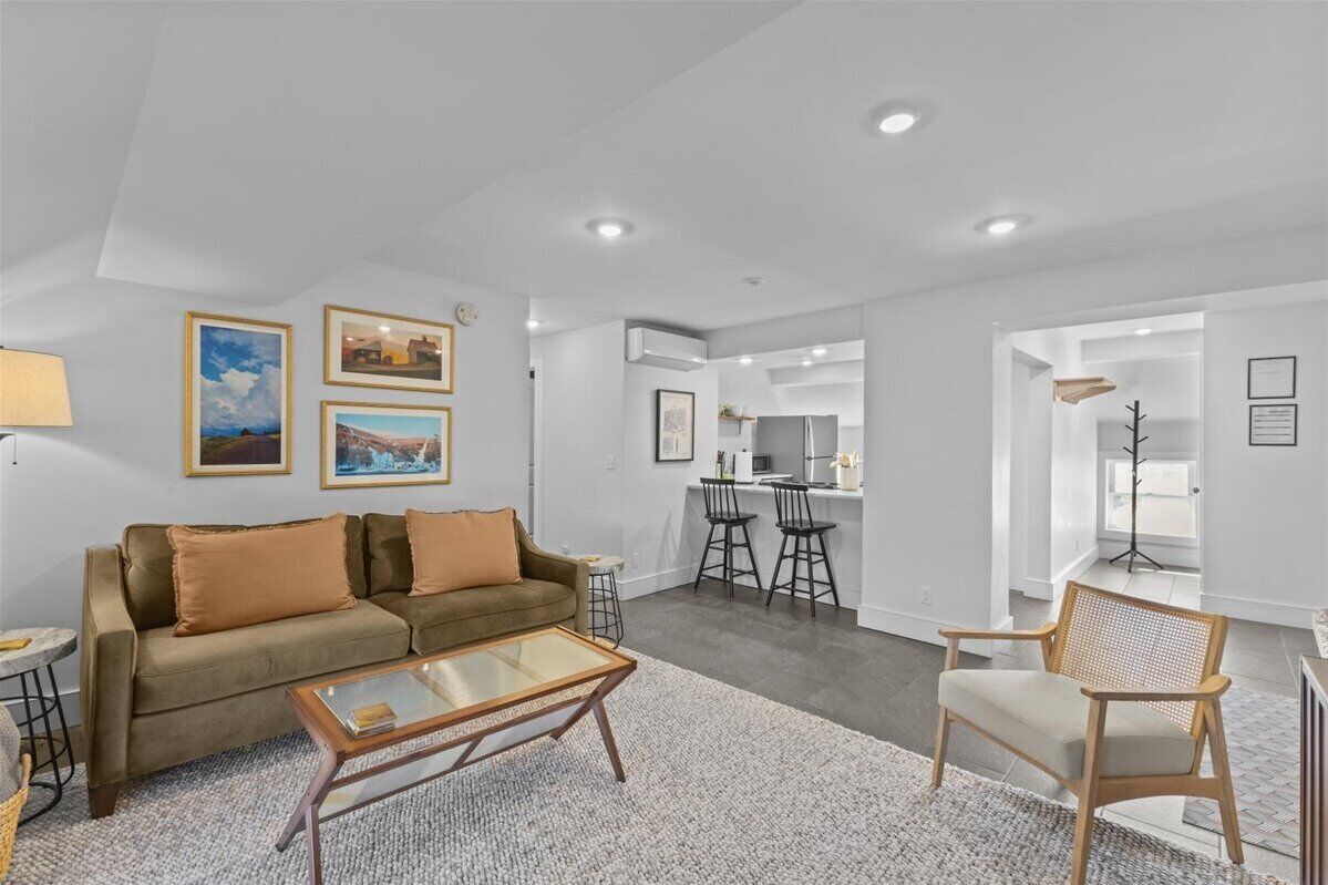 A modern living room with a sofa, coffee table, and a dining area with chairs.