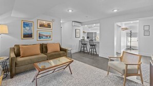 A modern living room with a sofa, coffee table, and a dining area with chairs.