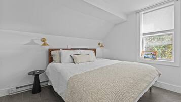 A bedroom with a bed, a small table, and a window with blinds.