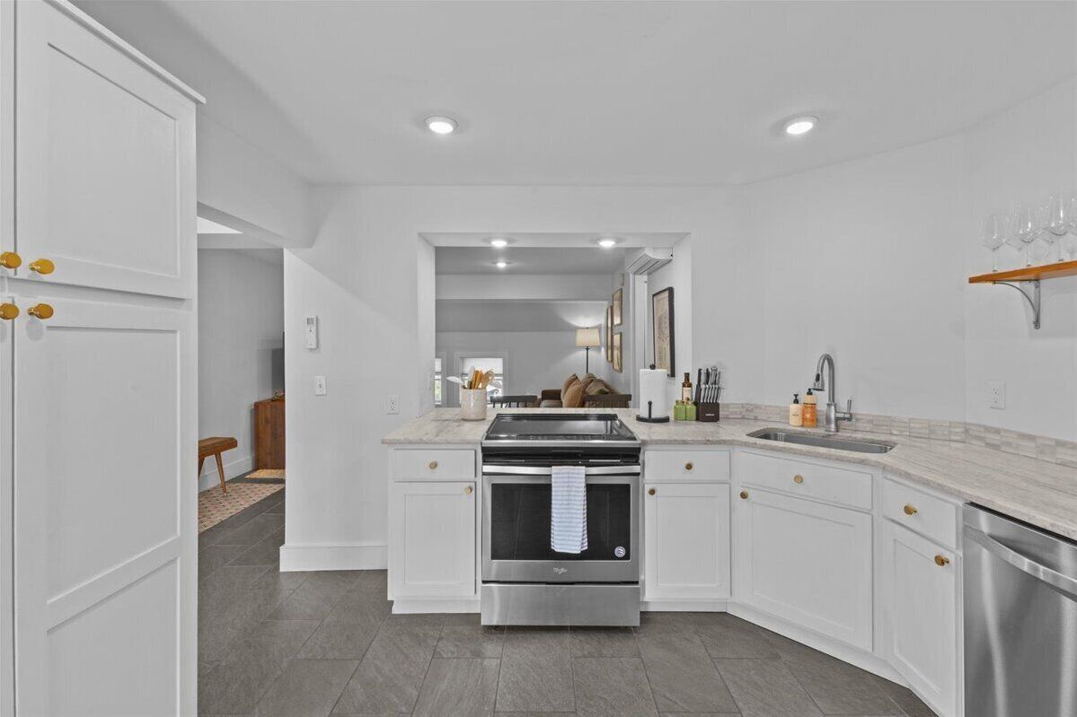 A modern kitchen with white cabinetry, a stainless steel stove, and a built-in oven.