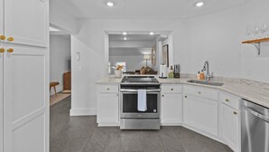 A modern kitchen with white cabinetry, a stainless steel stove, and a built-in oven.