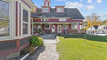 A two-story building with a red and white facade, a black roof, and a small porch area.