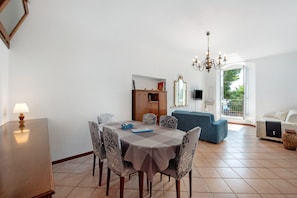 Un coin repas avec une table, des chaises et un lustre. On y trouve également un canapé et une fenêtre donnant sur un beau paysage.