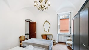 Une chambre avec deux lits, un lustre, un miroir, une fenêtre donnant sur un beau paysage et une armoire.