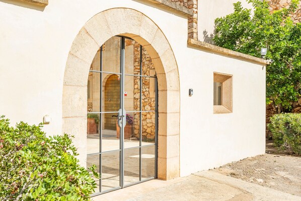 A building with a stone facade, a large arched entrance with glass doors, and a small window to the right.