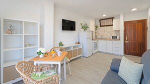 A modern kitchen with white cabinets, a flat-screen TV, and a wooden door.