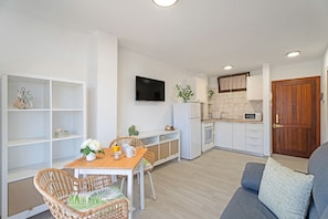 Une cuisine moderne avec des meubles blancs, un téléviseur à écran plat et une porte en bois.