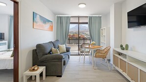 A modern living room with a sofa, a dining table, and a TV.