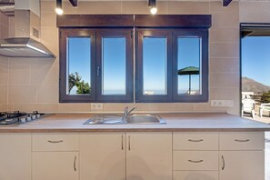 A kitchen with a large window, a gas stove, and a sink. - 'Casa Eyden Sunset View' with Private Terrace and Wi-Fi (Arona)