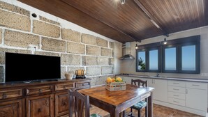 Una cucina con parete in pietra, mobili in legno, un tavolo da pranzo e un televisore.